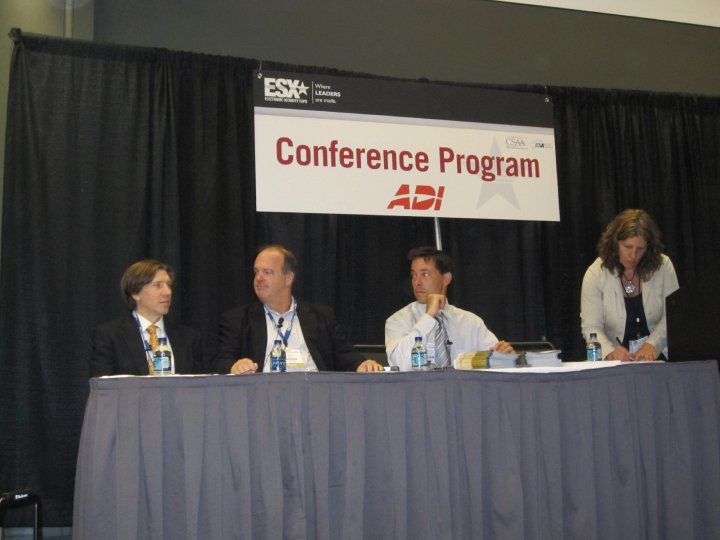 Panelists seated at a conference table under a program banner.