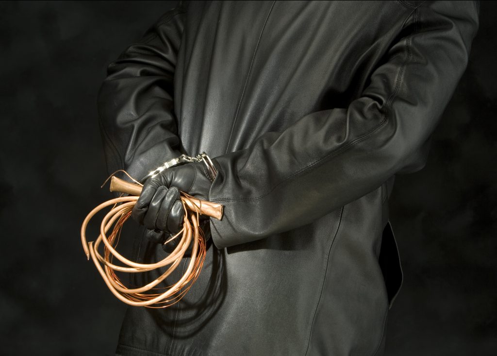 Person in black holding copper wires behind their back.