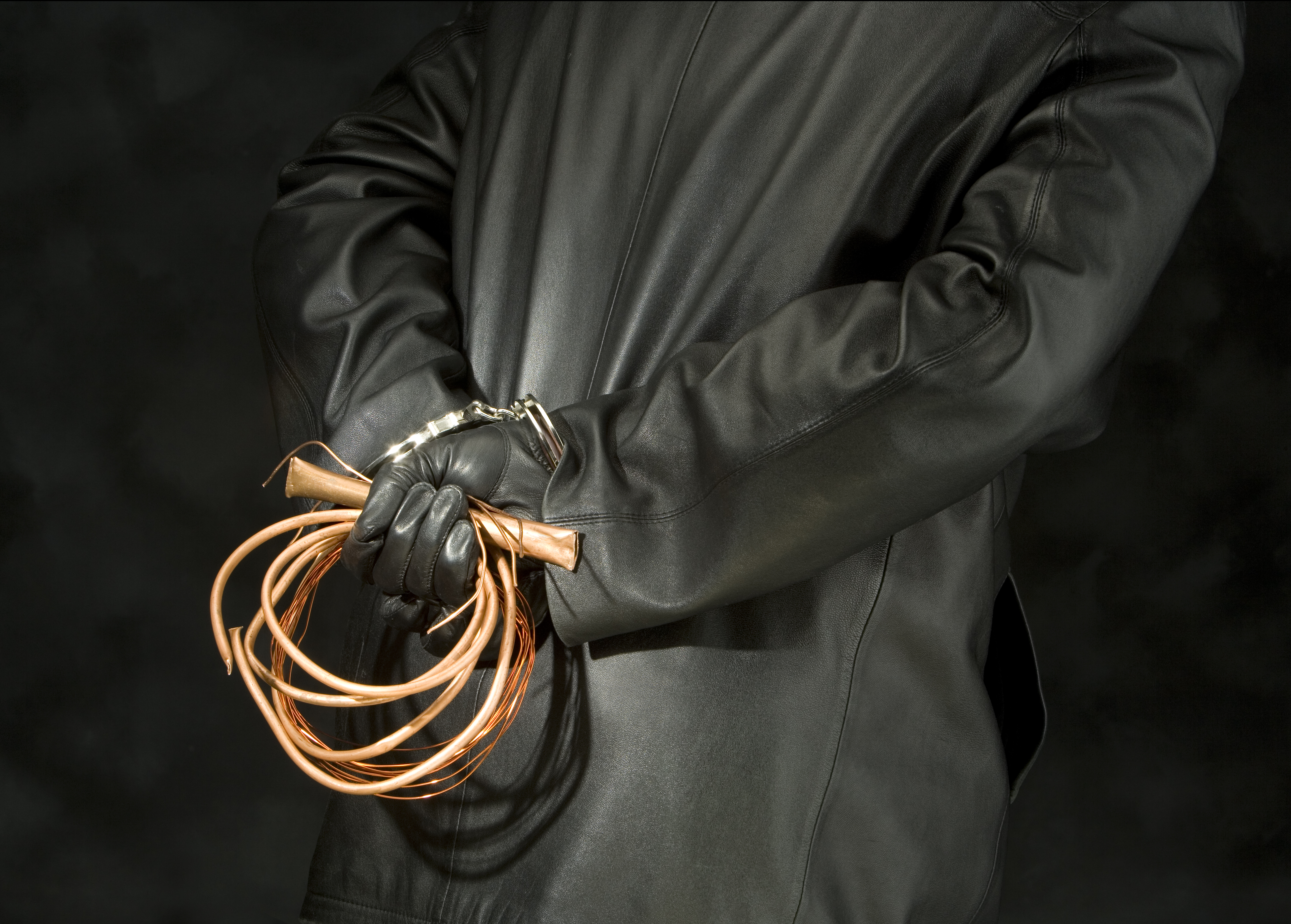 Person in black holding copper wires behind their back.