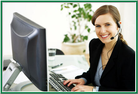 A woman with a headset working at a computer in an office.