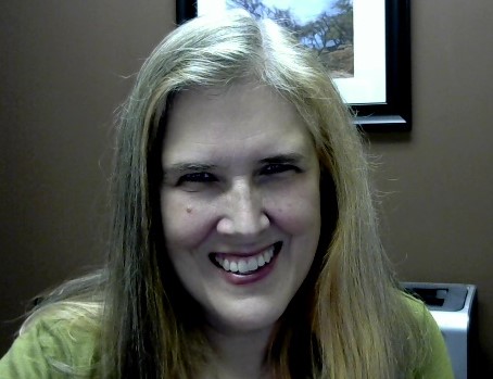 Smiling woman with long blonde hair indoors.