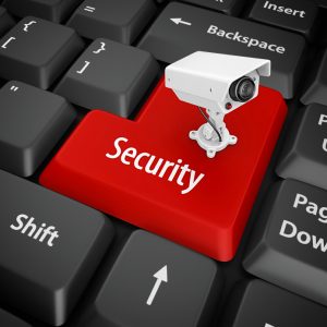 Red security key on keyboard with CCTV camera symbolizing digital security.