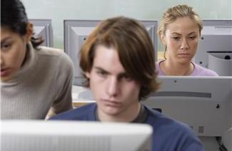 Three people focused on computer screens in an office setting.